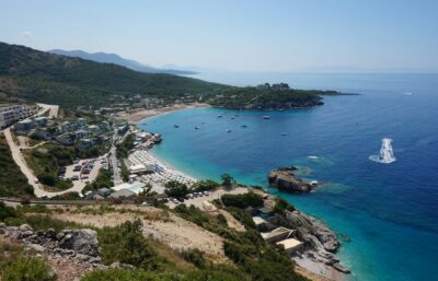 La nuova legge sul turismo del 2026: una veduta del litorale albanese con una spiaggia e strutture ricettive.