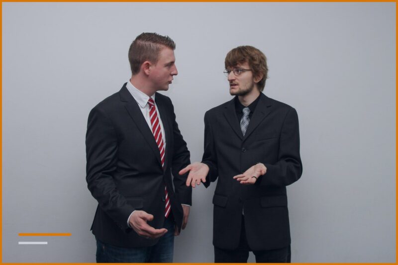 Two professionals in suits in an open-armed discussion.