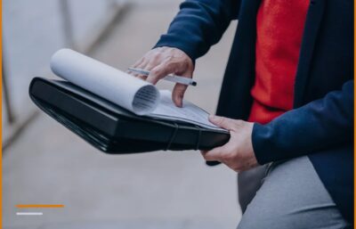 Un imprenditore che esamina documenti e fatture contenuti in una cartellina fuori dai locali dell'azienda.