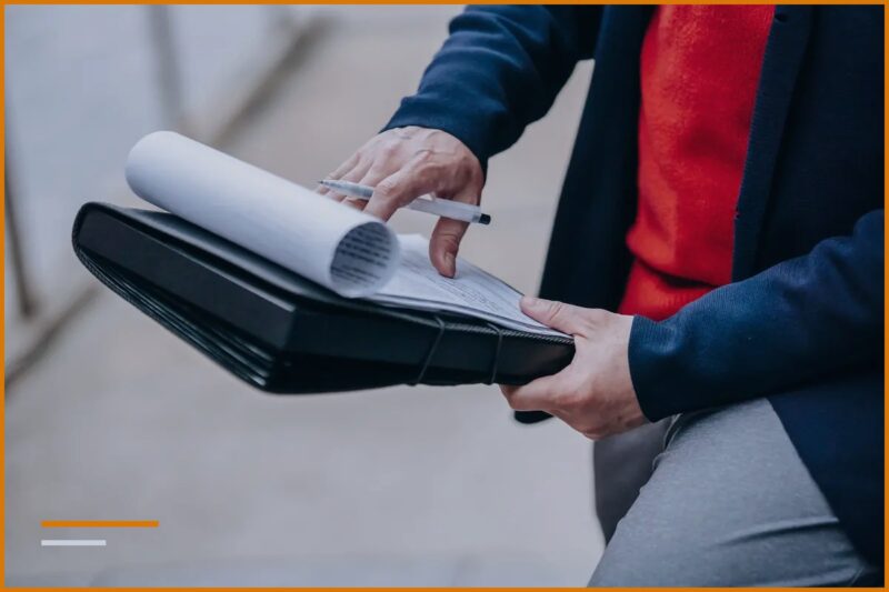 Business owner reviewing documents and invoices in a folder outside the business premises.