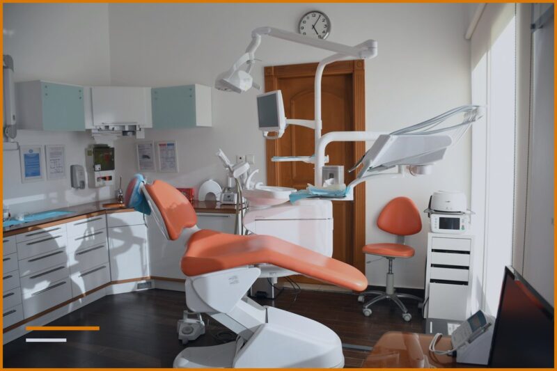 Ambient i një klinike dentare me karrige portokalli dhe pajisje mjekësore