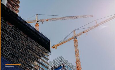 Dy vinça kullë portokalli mbi një ndërtesë në ndërtim e sipër, parë nga poshtë, me skelat e fasadës në plan të parë