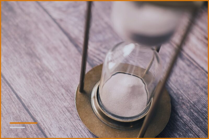 Bronze hourglass with sand on a wooden table, time that flows
