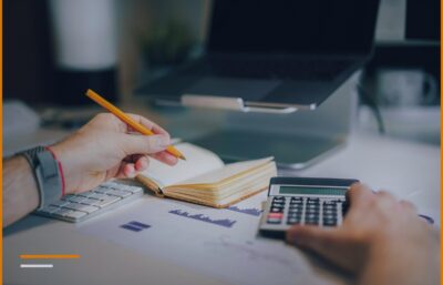 Hands holding a pencil over a notepad next to a calculator, calculating the days in the report.