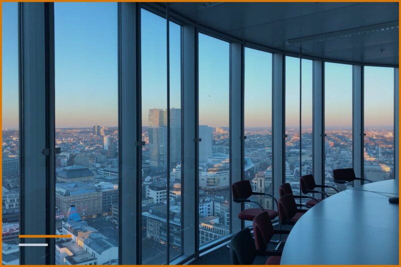 Una sala riunioni vuota con un tavolo rotondo e finestre panoramiche affacciate sulla città.