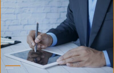 Punëdhënës me kostum nënshkruan mbi një tablet, kostoja e punonjësit