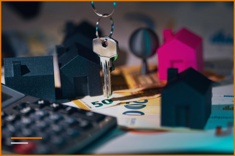 Key, house models, and euro banknotes next to a calculator